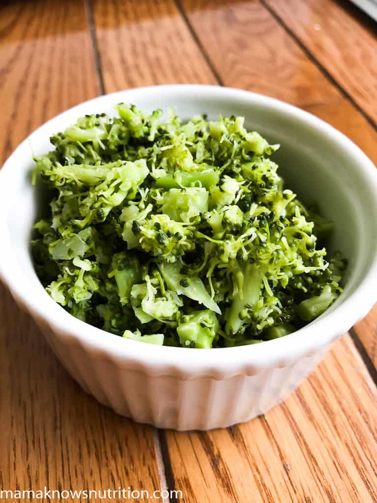 bowl of chopped cooked broccoli on table