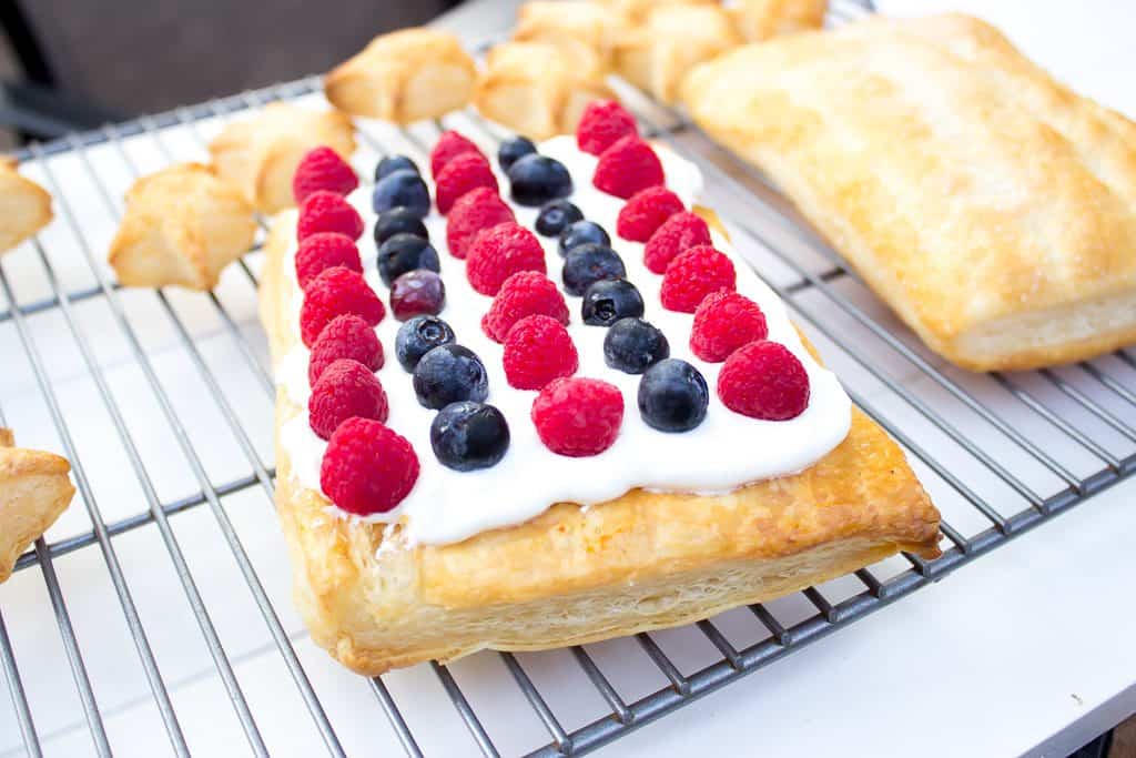 A piece of cake sitting on top of a cutting board, with Pastry and Berry