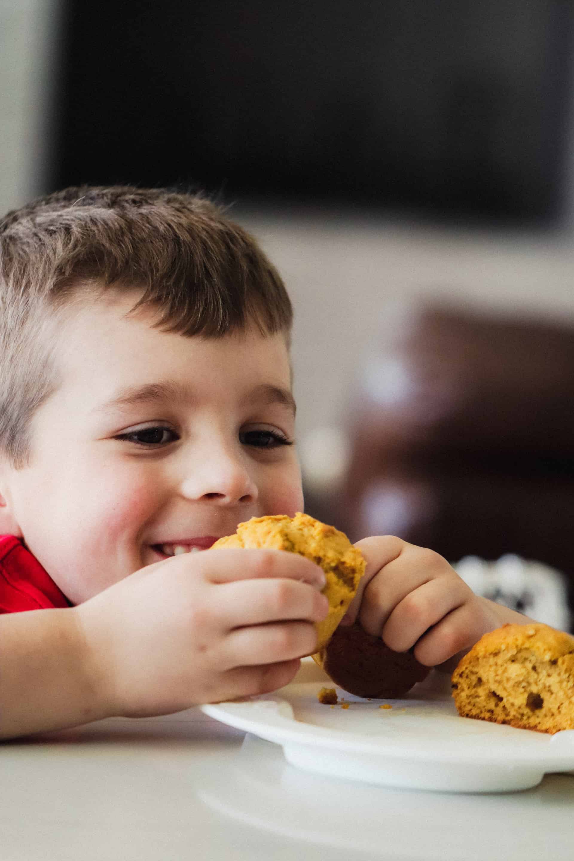 boy sitting at table with healthy toddler muffin thats easy and picky eater friendly