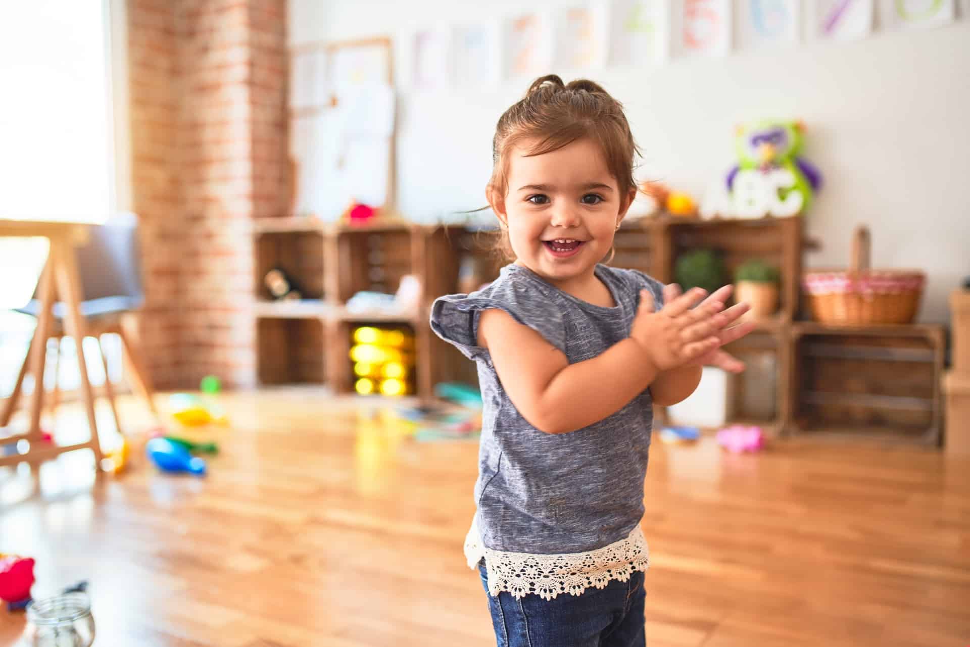 A little girl standing in a room toddler at daycare