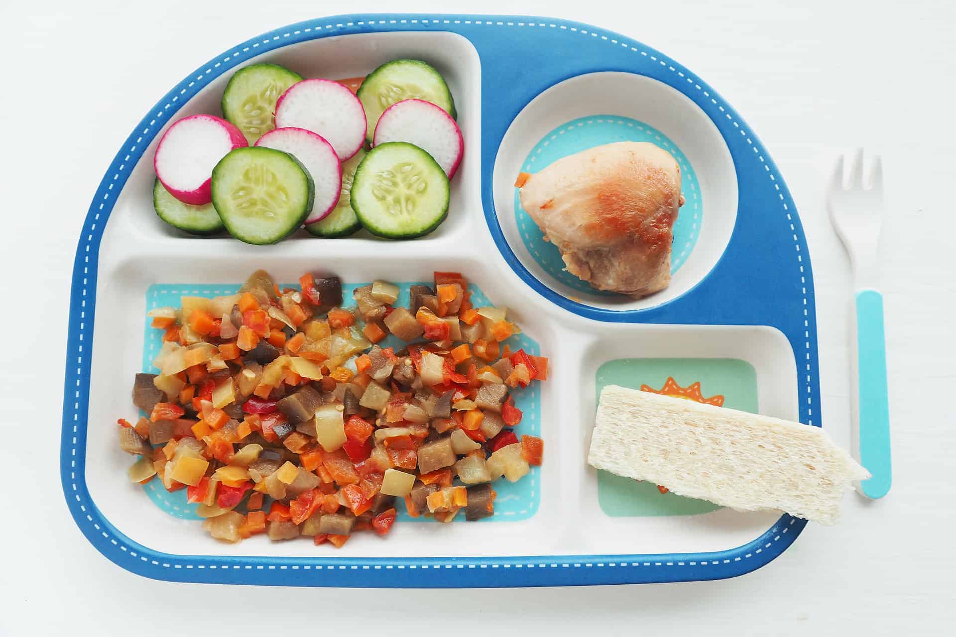 A plate of food on a table with veggies, and meat in different sections