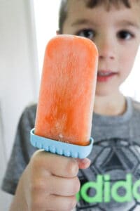 kid holding homemade orange popsicle