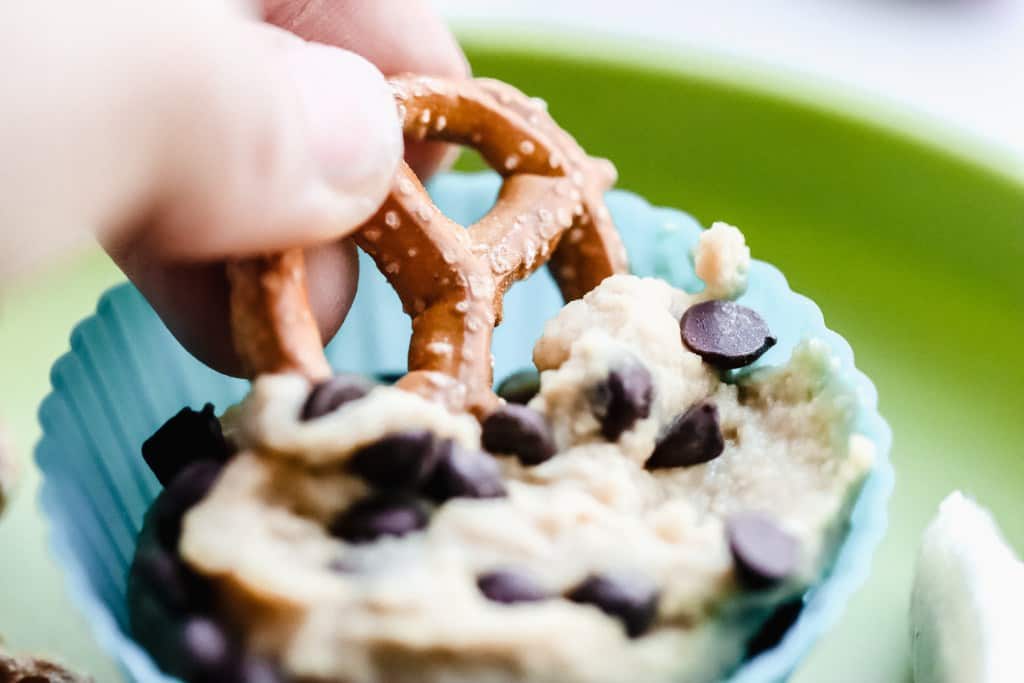 kid dipping pretzel in cookie dough