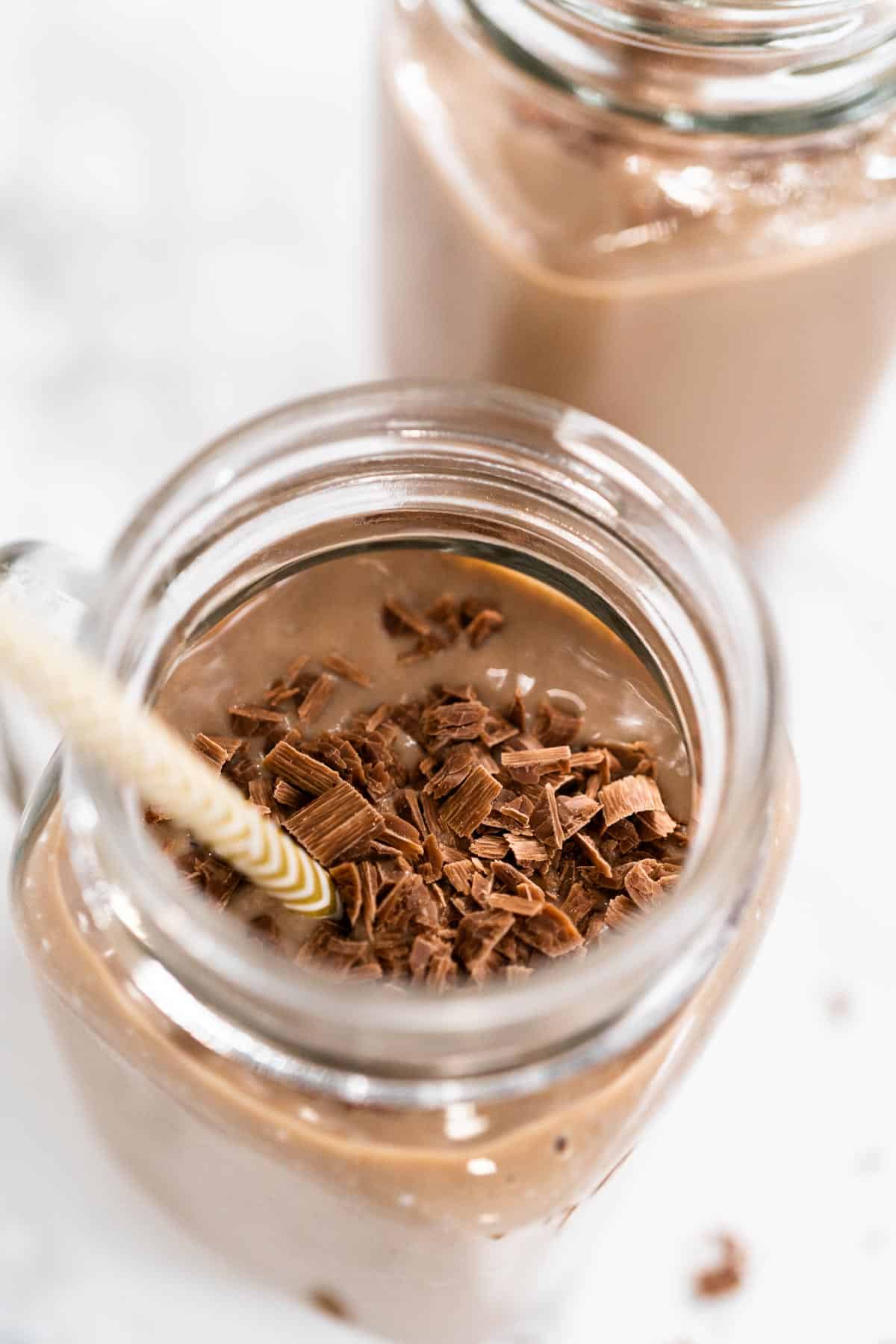 2 mason jars of healthy chocolate smoothie aerial view with chocolate shavings