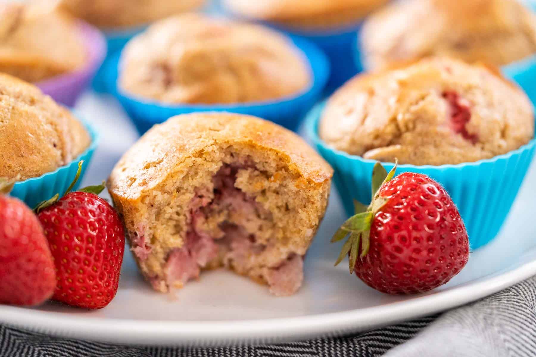 strawberry muffins on plate with strawberries and silicon muffin cups