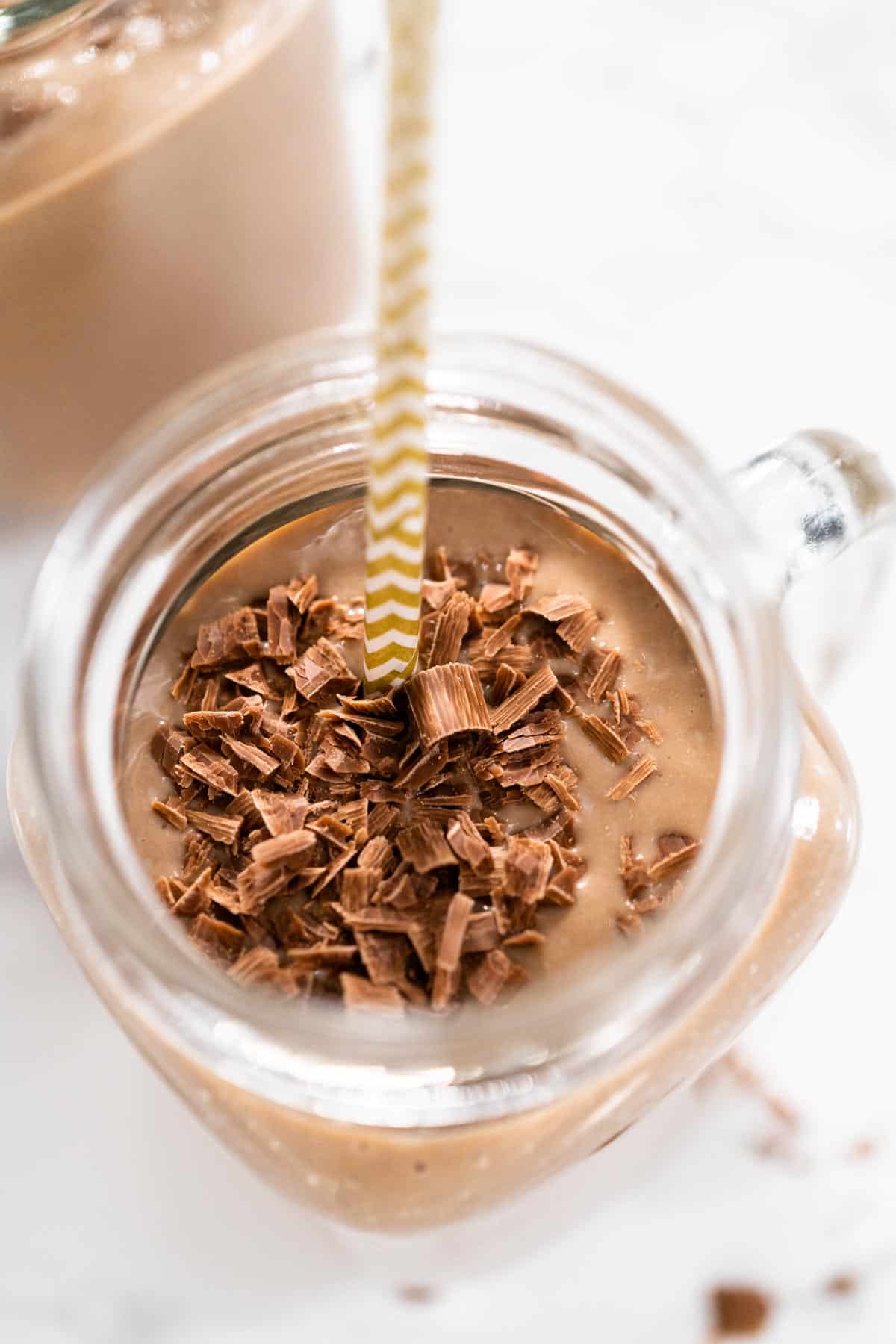 healthy chocolate smoothie recipe with chocolate shavings in a glass jar with white background 