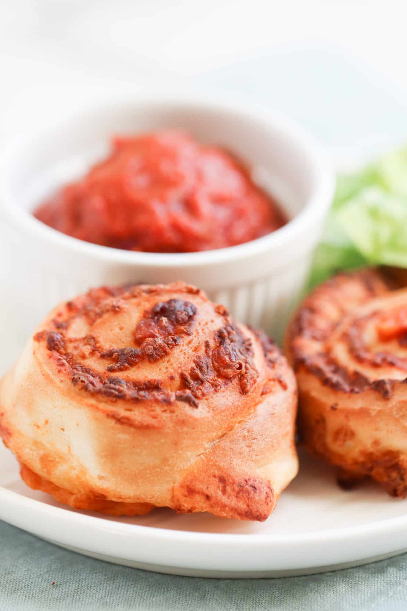 air fryer pizza rolls on white plate with marinara sauce for dipping