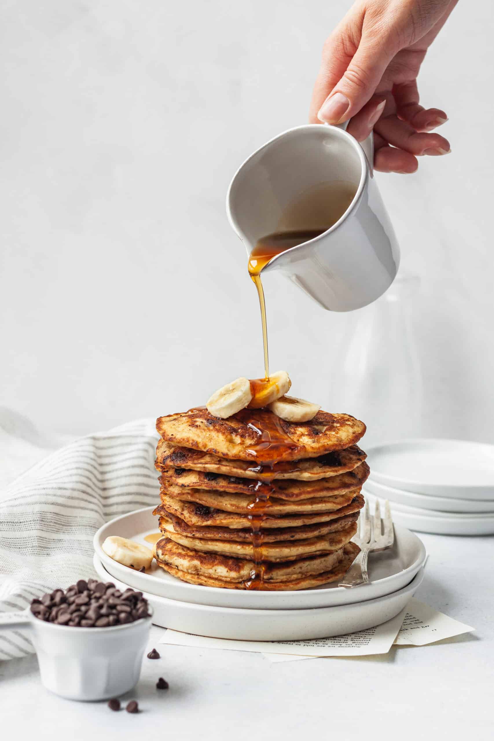 pouring syrup on banana chocolate chip pancakes