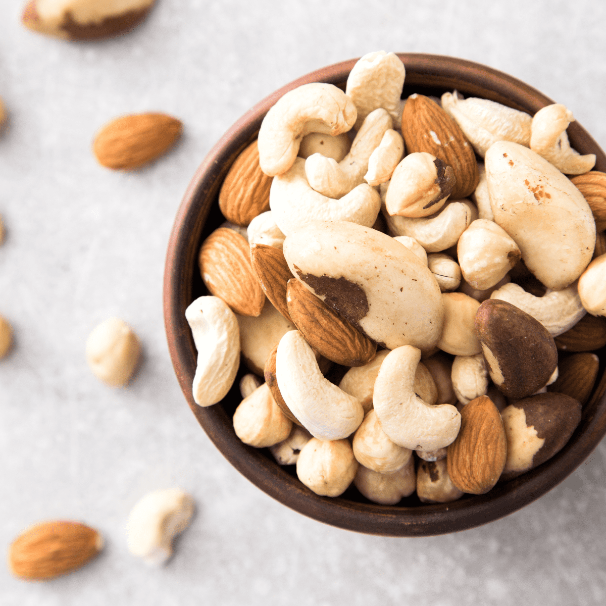 Brown bowl on countertop with mixed nuts