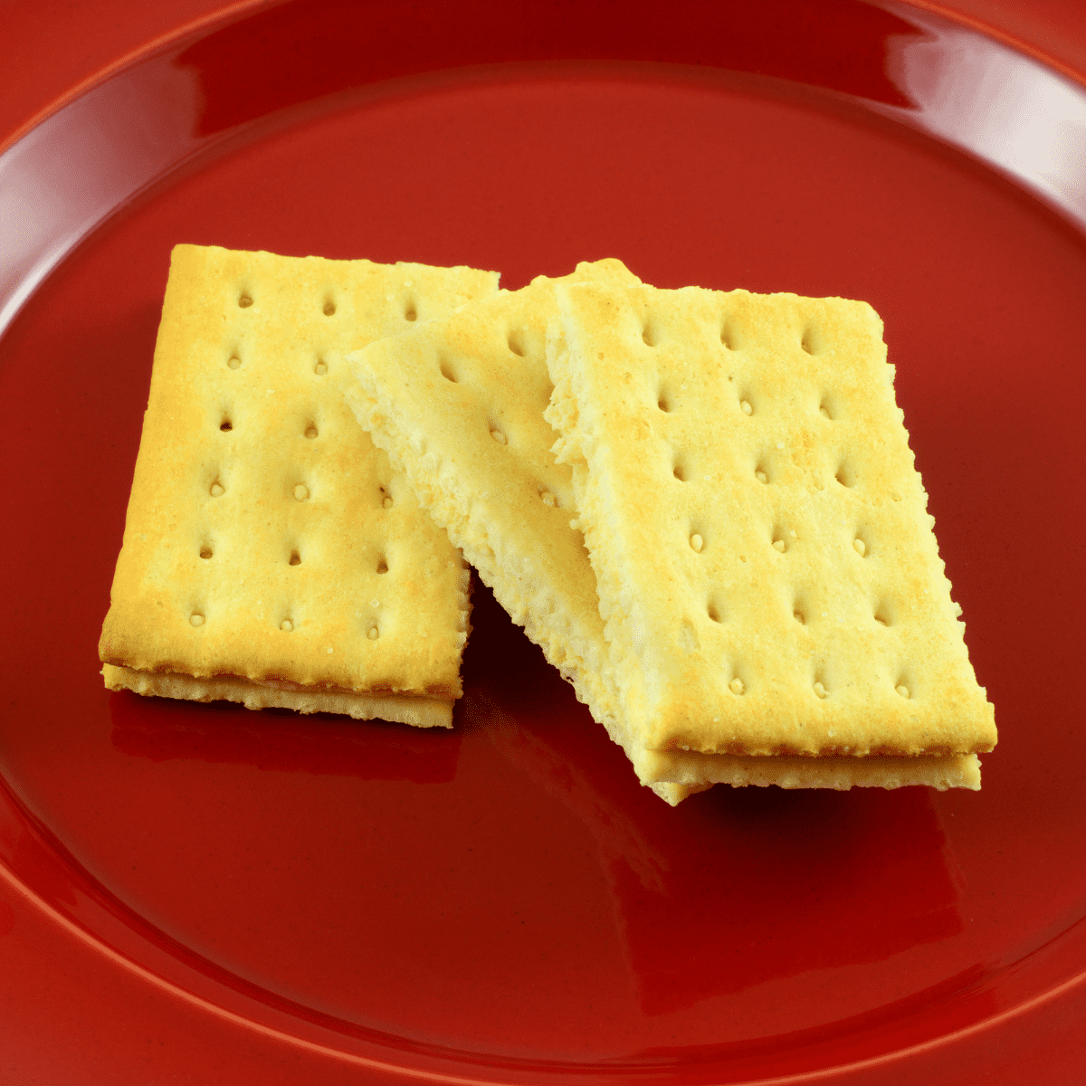 Three rectangular cracker sandwiches on a red plate