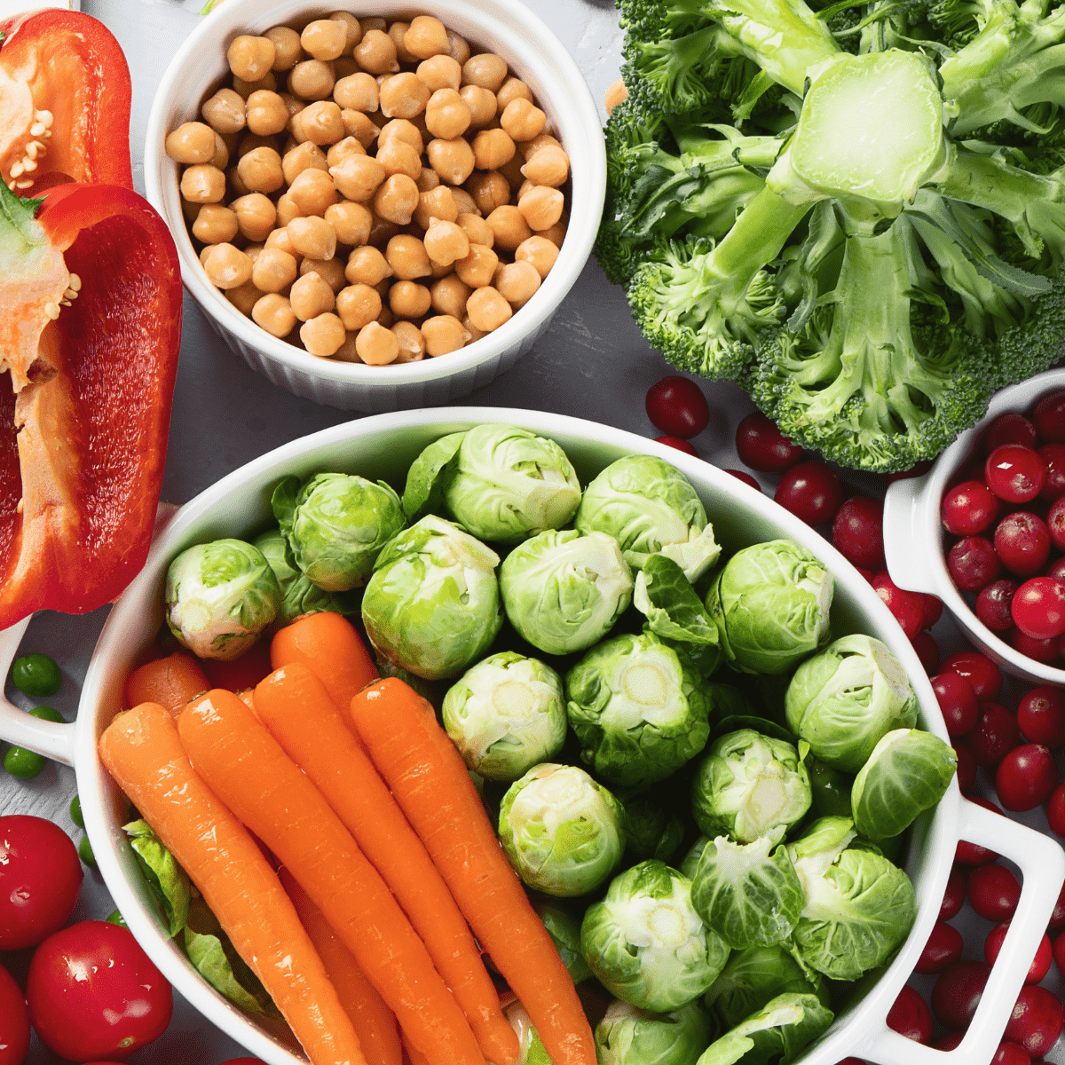 Table of vegan food - carrots, brussel sprouts, chickpeas, broccoli, tomatoes, red pepper