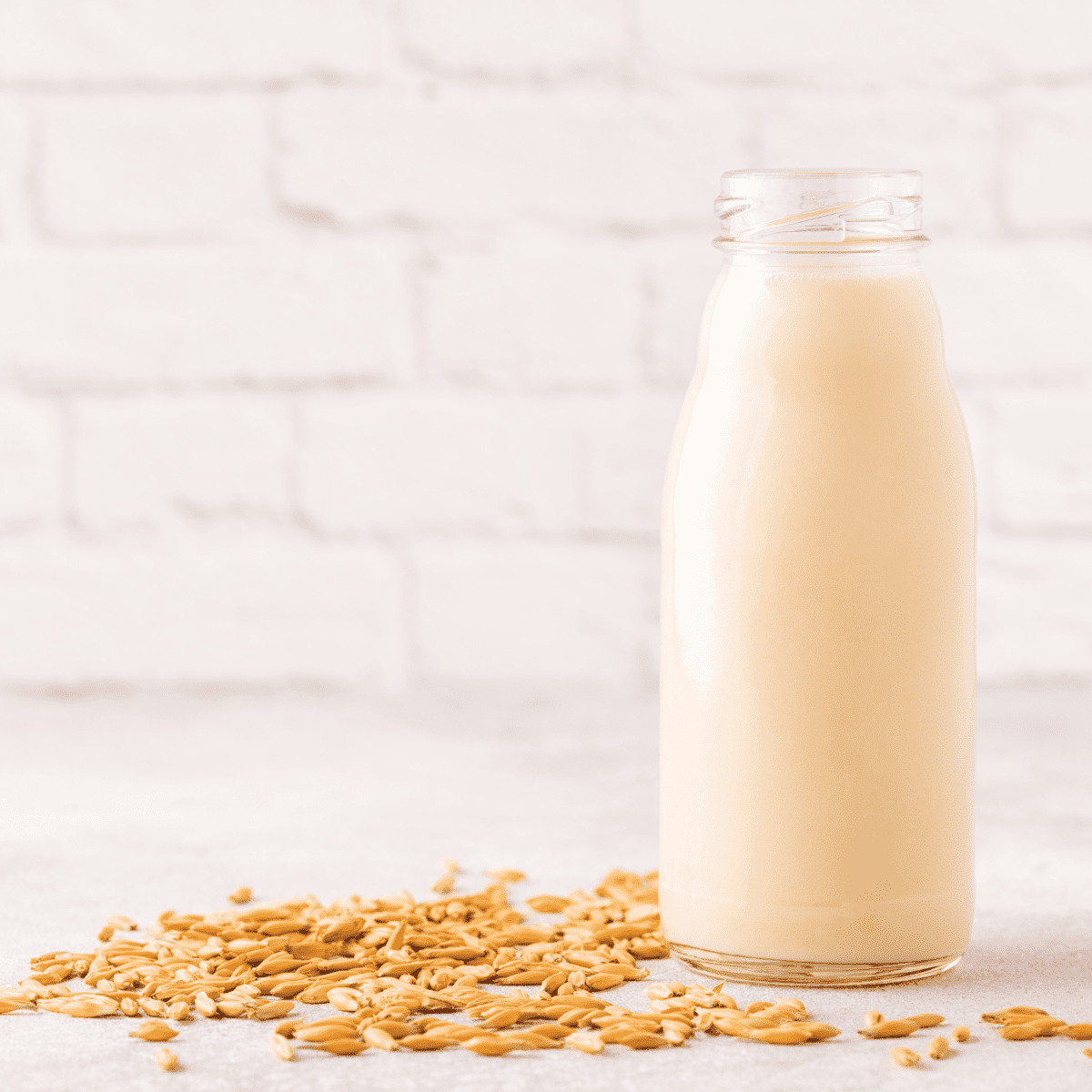 Oat Milk in Glass Jar with Oats Scattered On Table