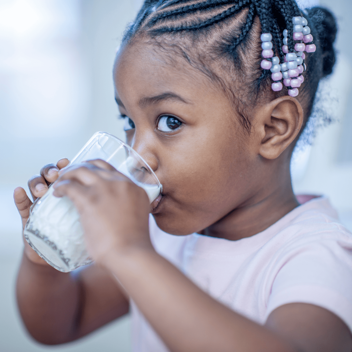 Young girl in pink shirt drinking a glass of milk