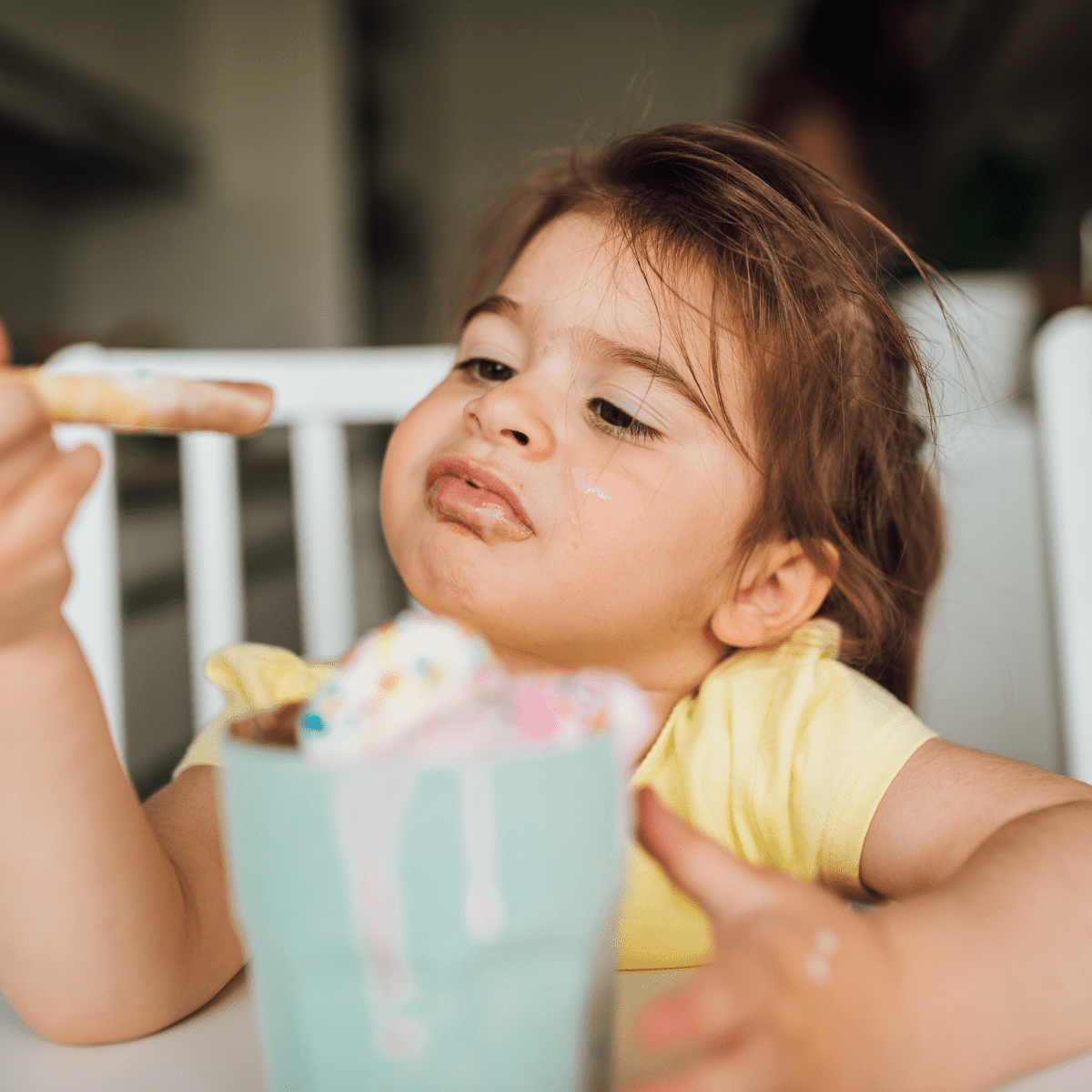 Toddler eating a milkshake out of a glass