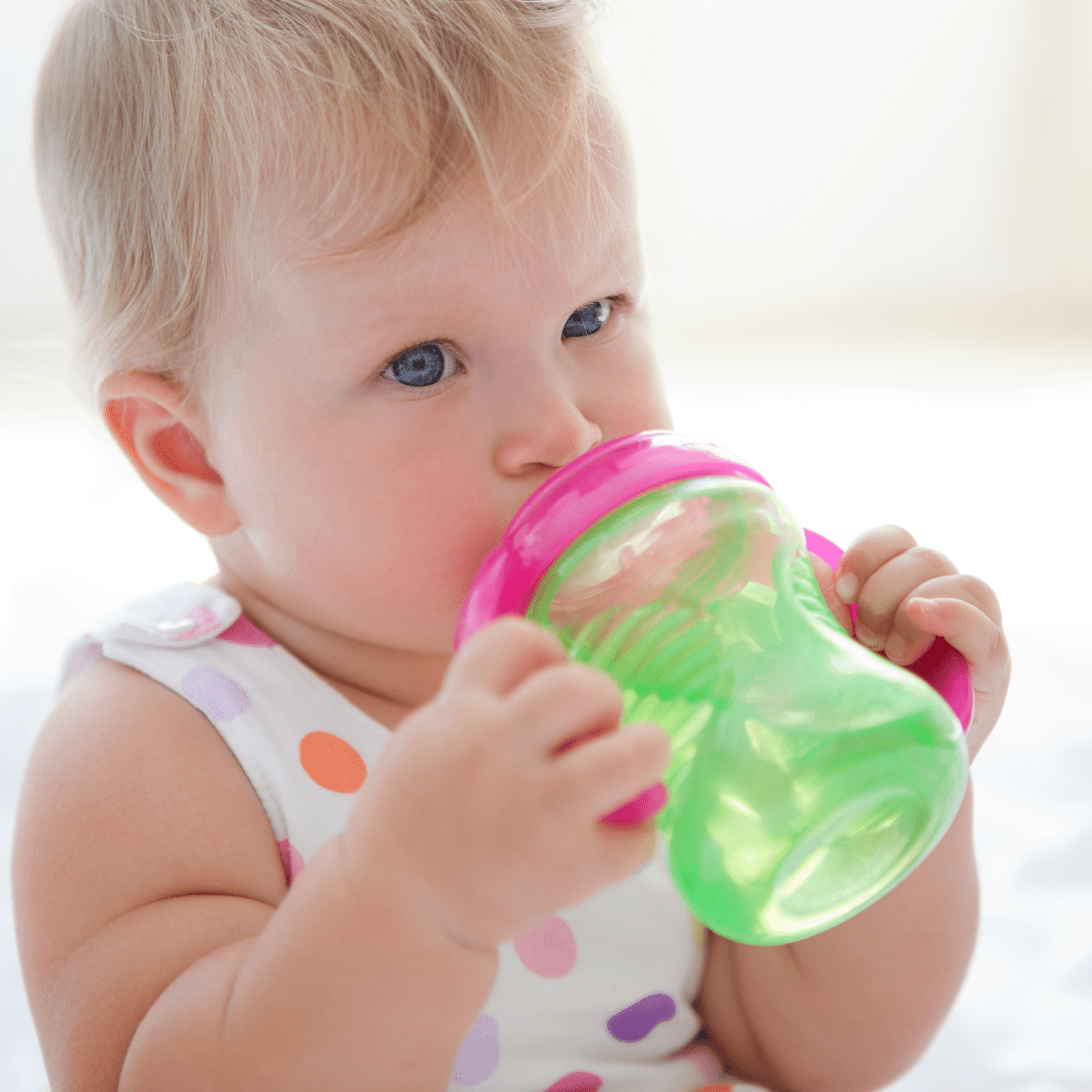 Young toddler drinking water from a sippy cup