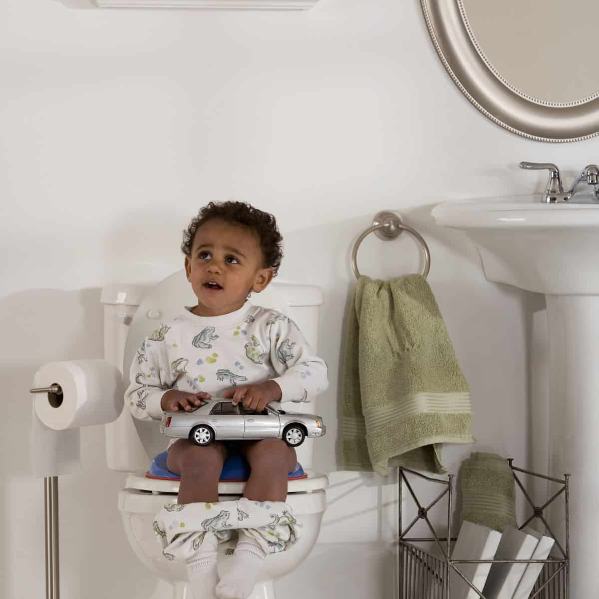 Little boy sitting on toilet with toy car