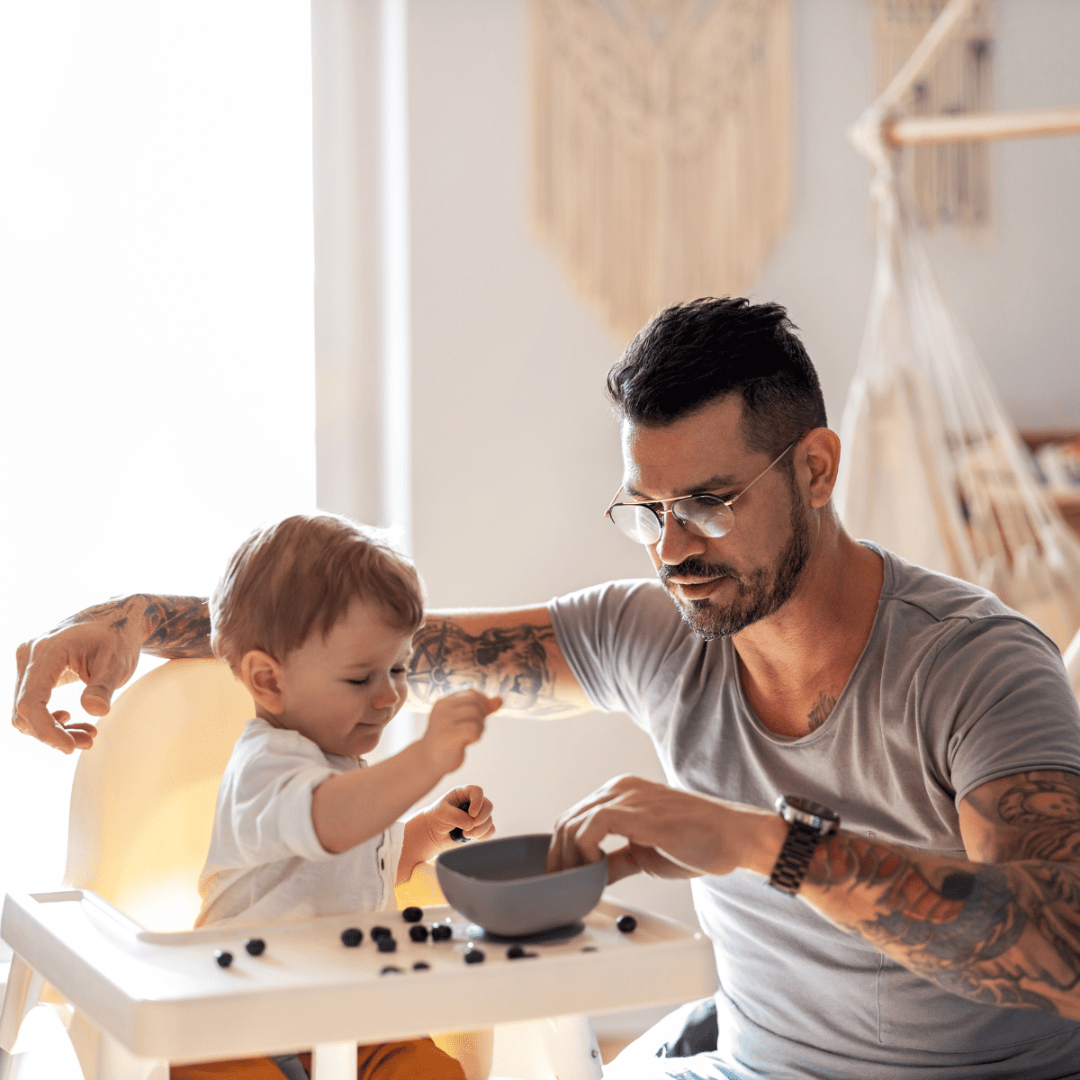 Father parenting a toddler berries in high chair