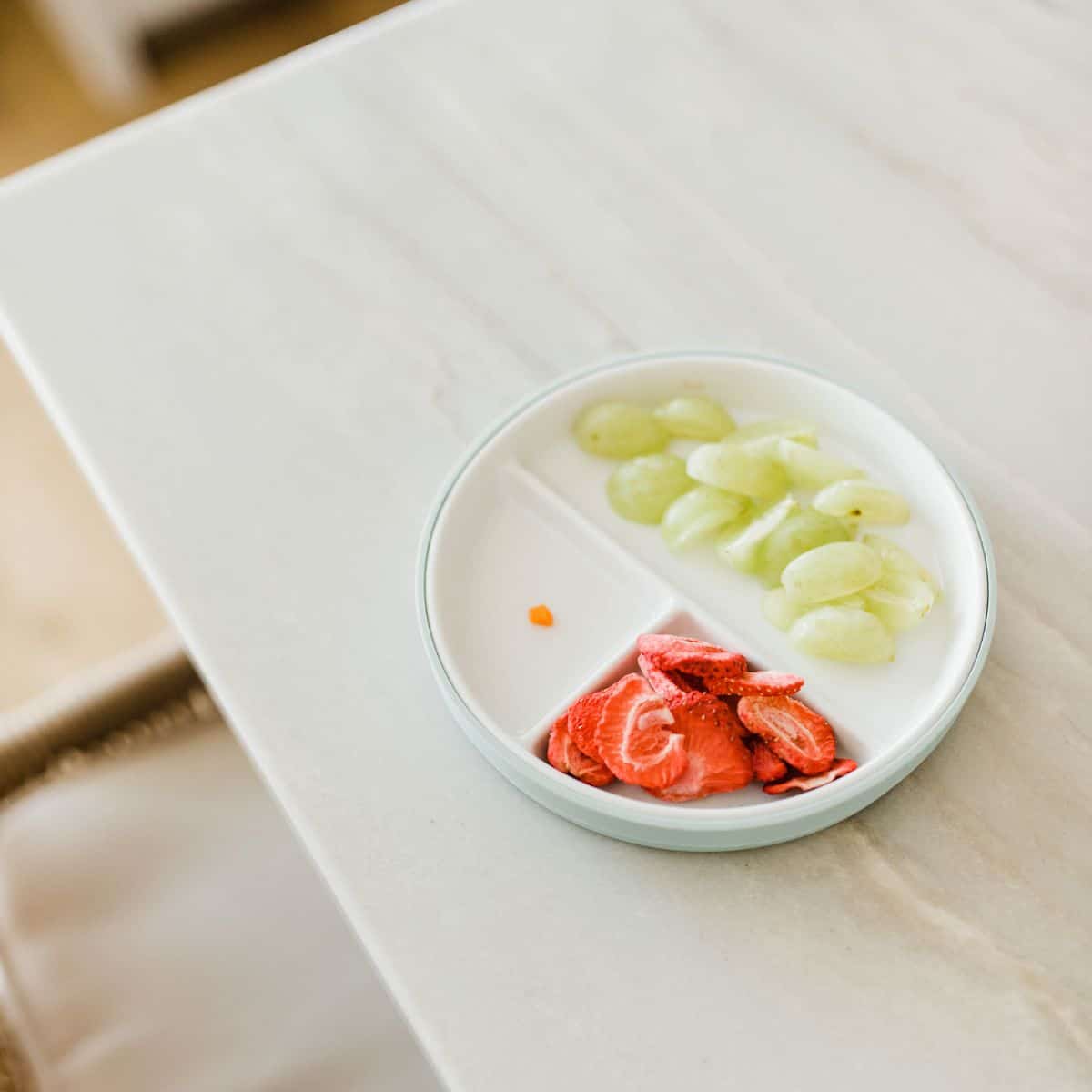 Plate with grapes, strawberries and a small piece of carrot