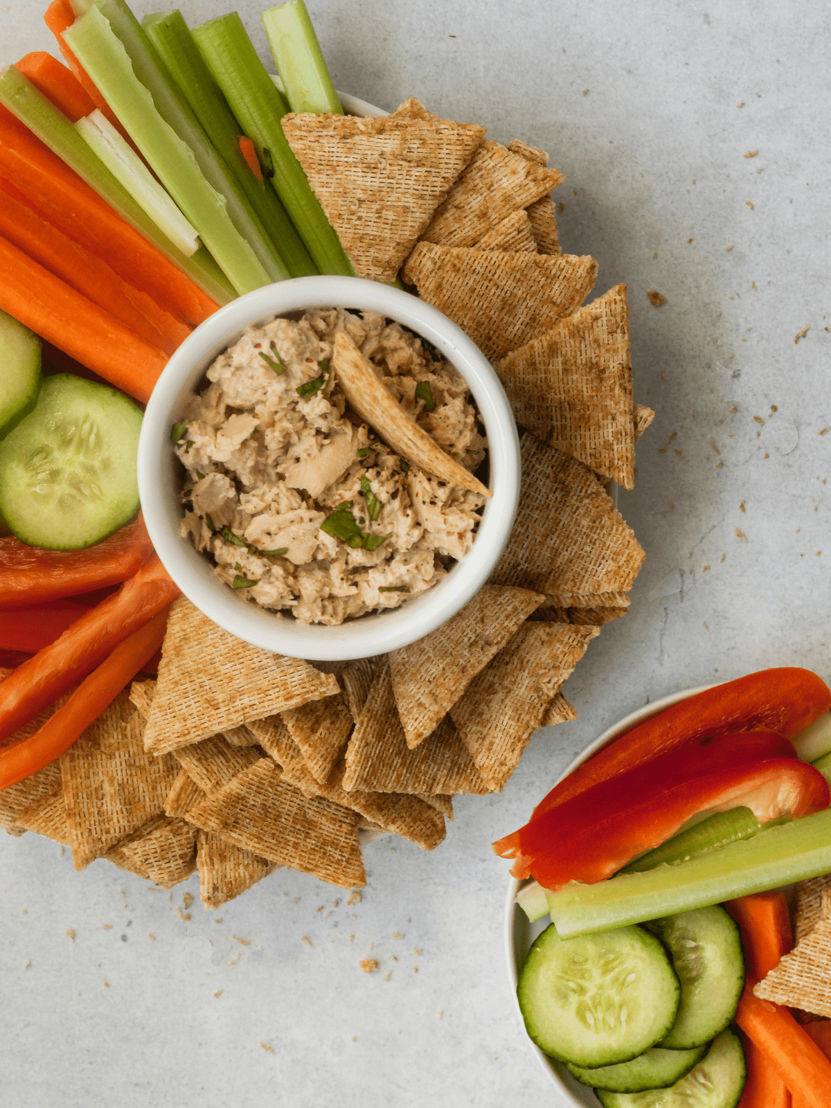 Top-down photo of canned salmon plated with crackers and veggies.