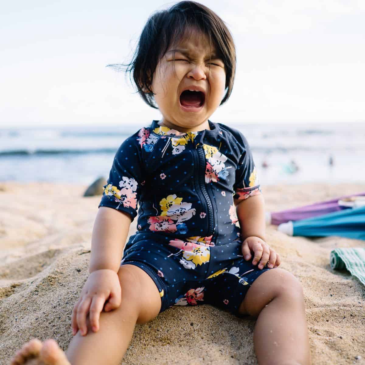 Toddler crying in sand on beach