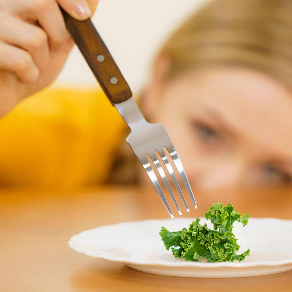 kid with fork and piece of kale 