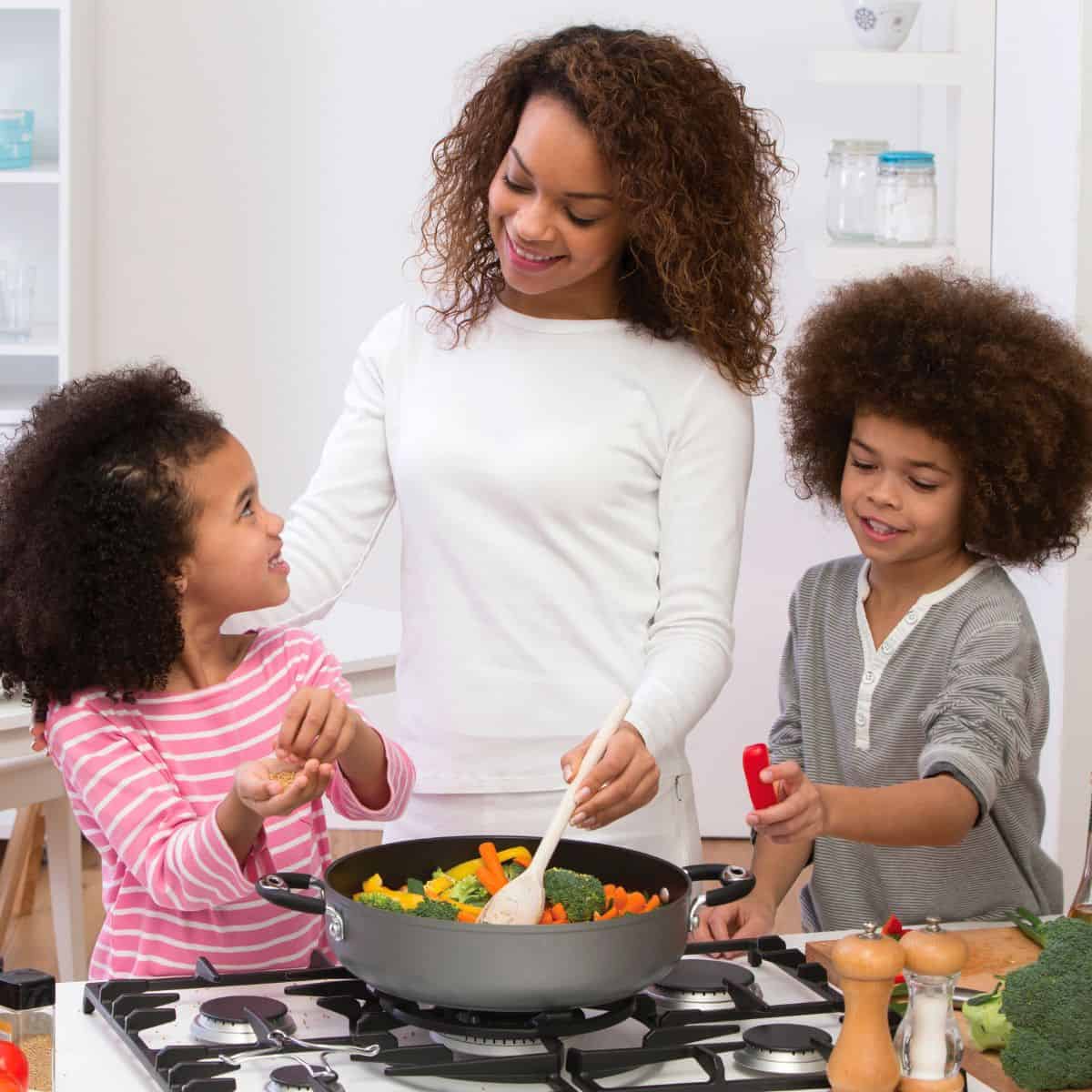 Mom, daughter and son cooking dinner together on the stove