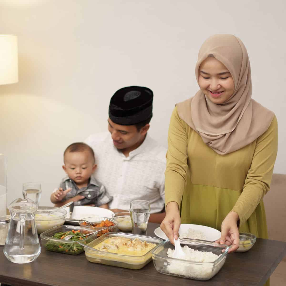 Mom, dad and child sitting together at a table serving a meal