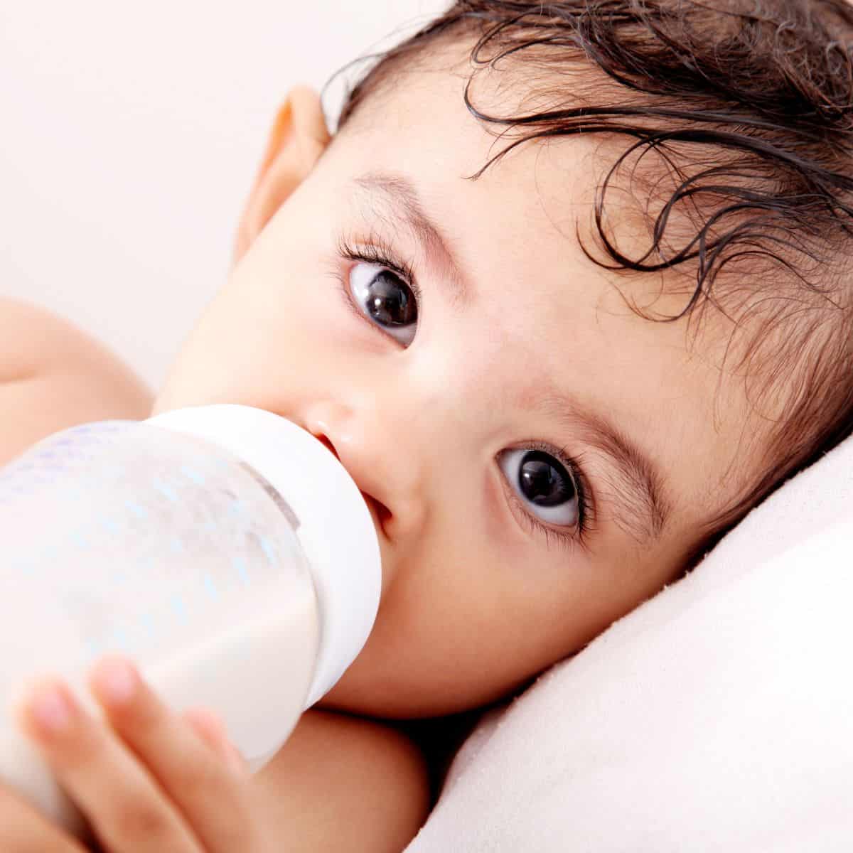 Baby holding bottle of milk