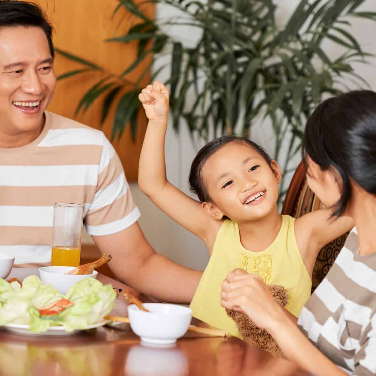 Mom, dad and daughter eating a meal together at a table