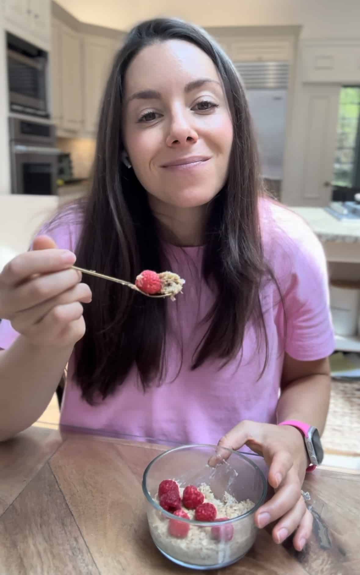 Kacie Barnes of Mama Knows Nutrition eating a bowl of microwave baked oatmeal topped with nut butter and raspberries