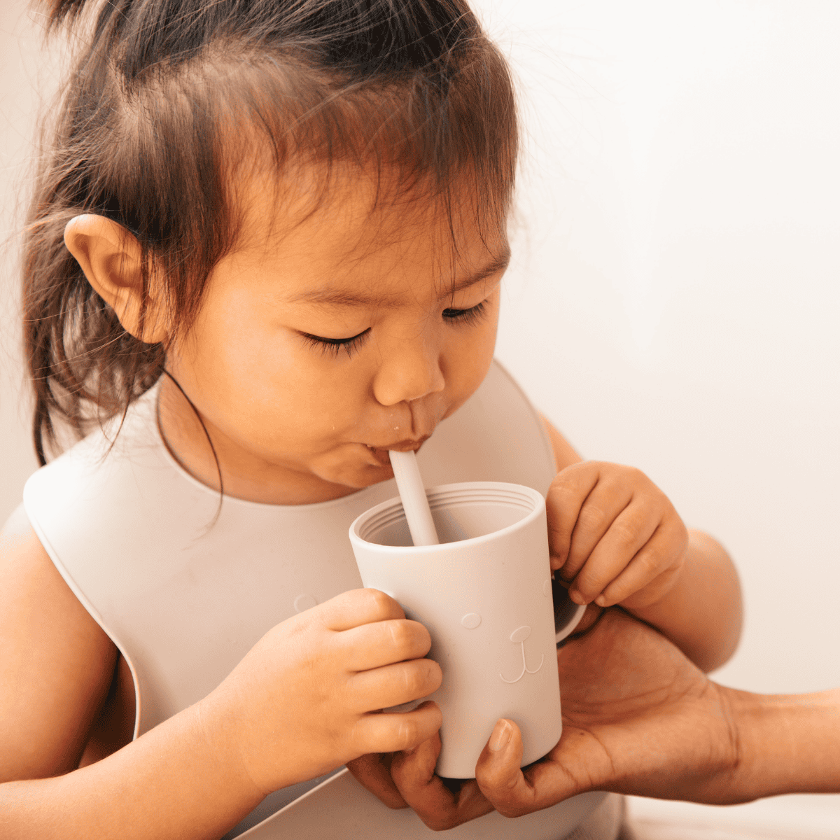 young girl drinking out of straw cups