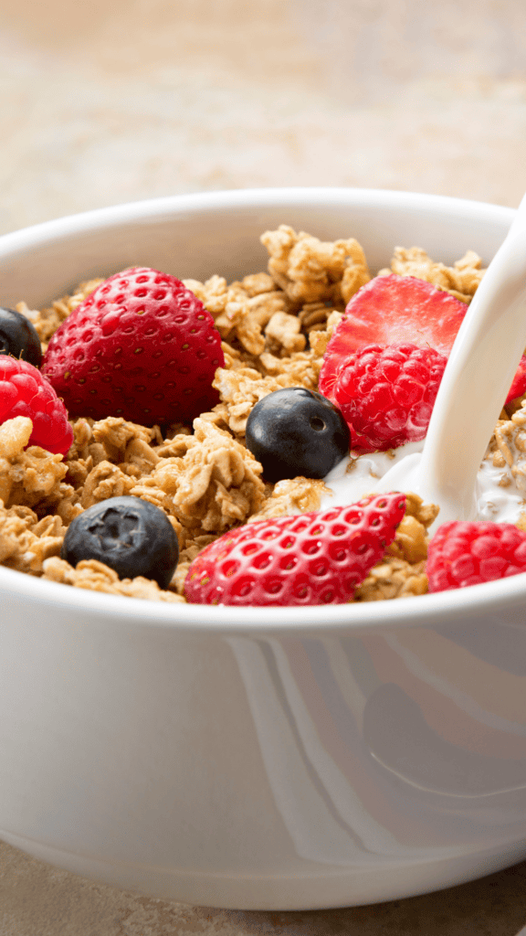 White Bowl of Cereal With Berries and Milk Pouring into Bowl