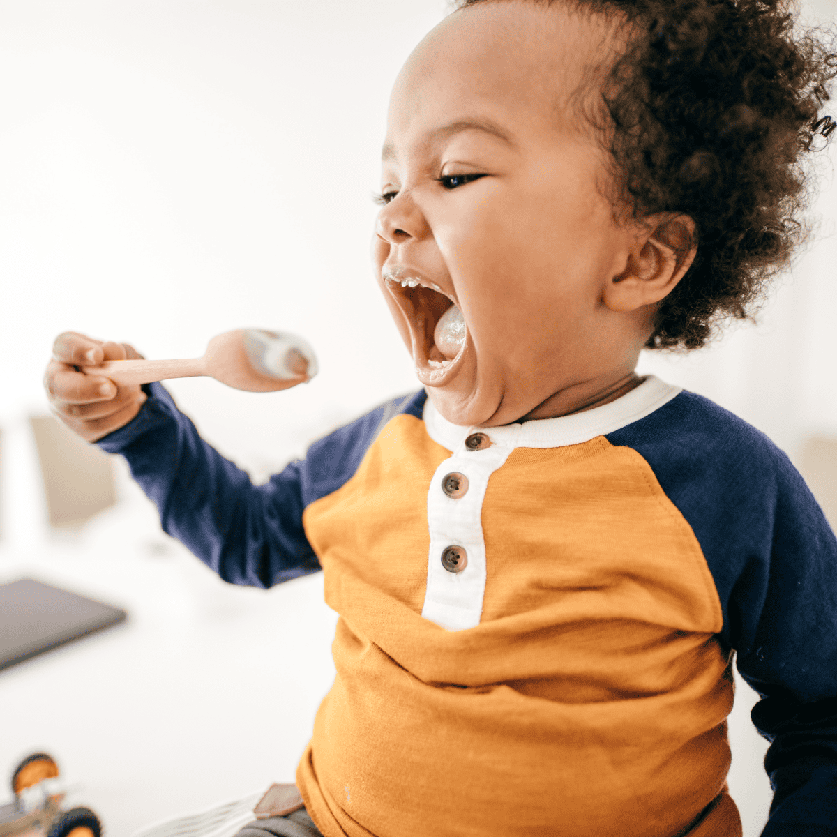 toddler eating with utensils