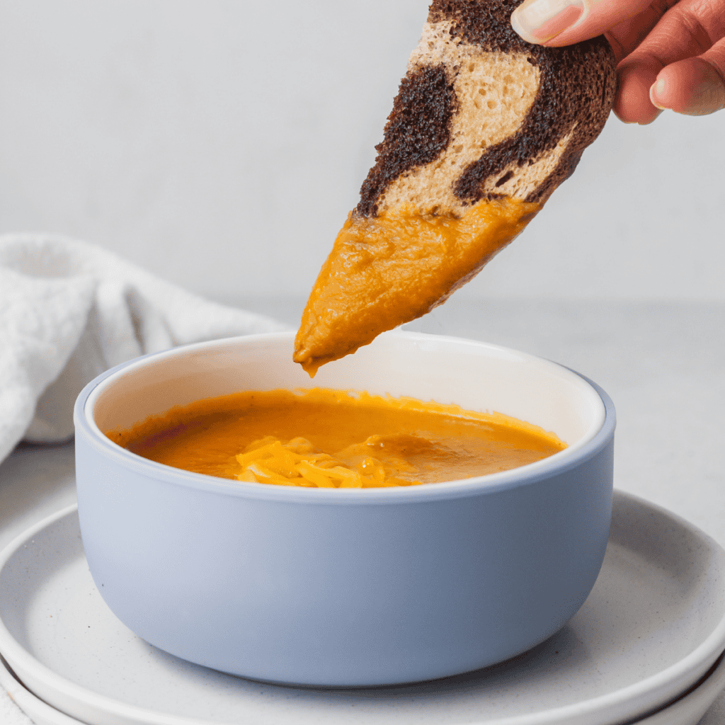 bread dipping into creamy pumpkin soup