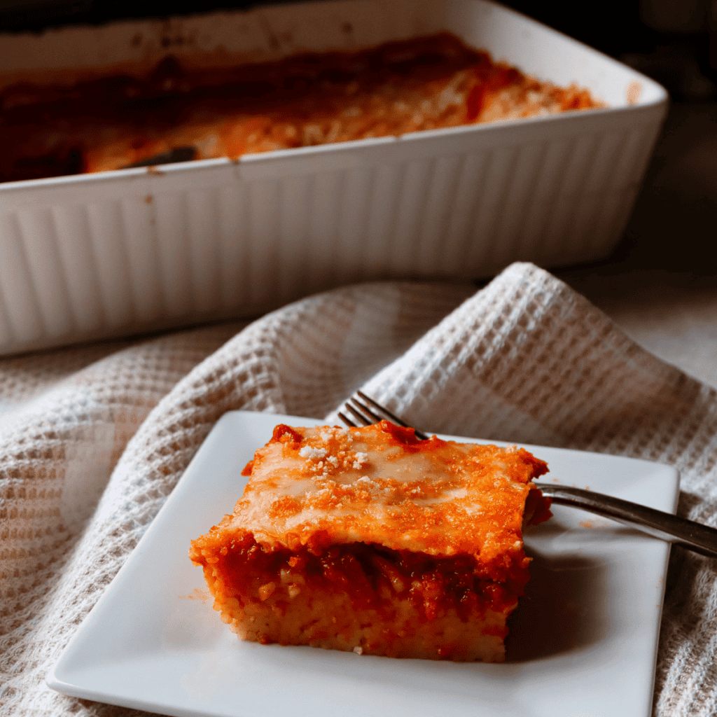 slice of spaghetti casserole on a plate with pan in the background