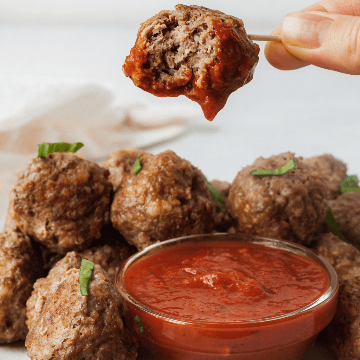 close up of mini meatball on a toothpick dipped in sauce