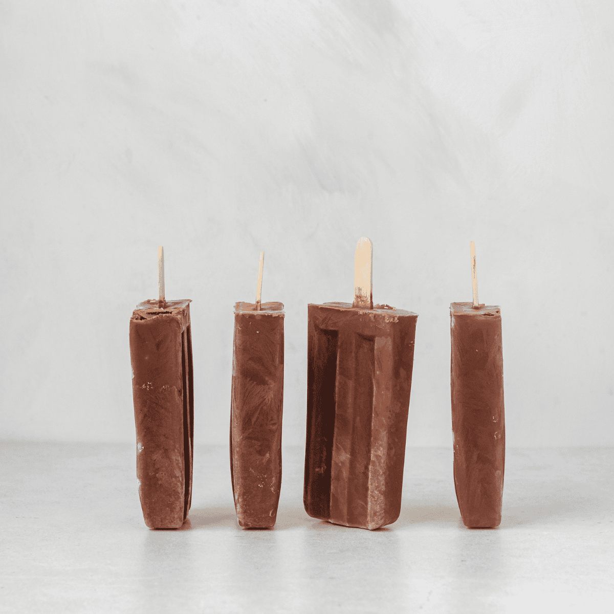 chocolate banana popsicles standing up on the counter