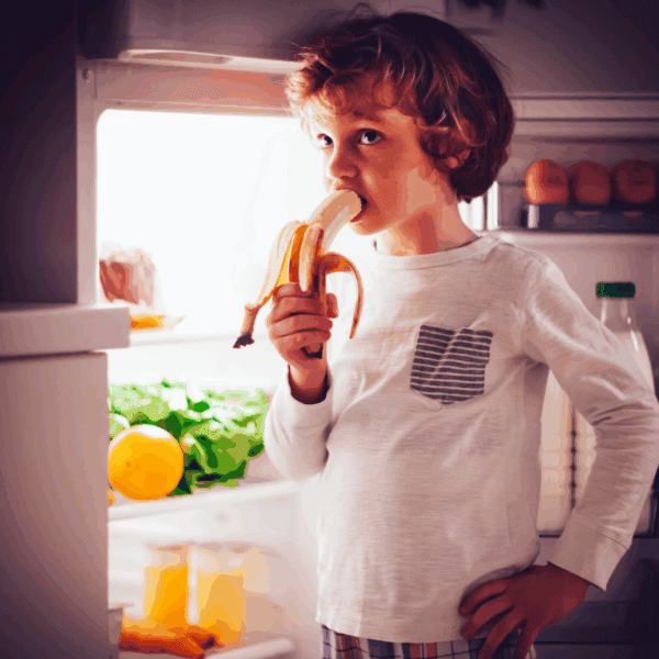 kid eating a bedtime snack with the fridge open